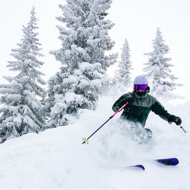 Skier in action on a snowy slope with trees